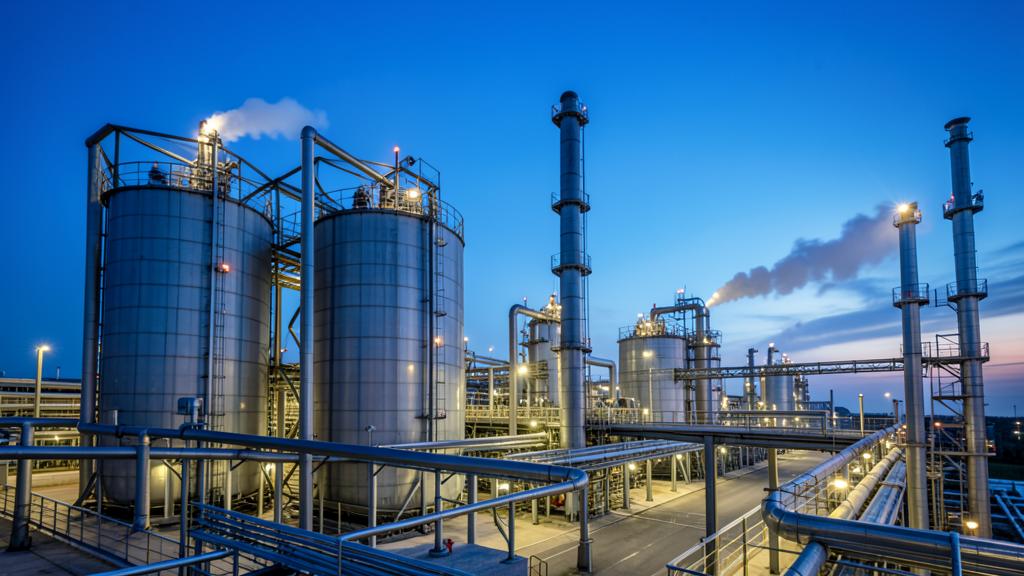 Petrochemical refinery storage tanks and pipework at dusk
